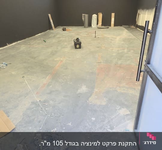 חלל עבודה עם רצפת בטון חשופה ופלס לייזר לפני התקנת פרקט